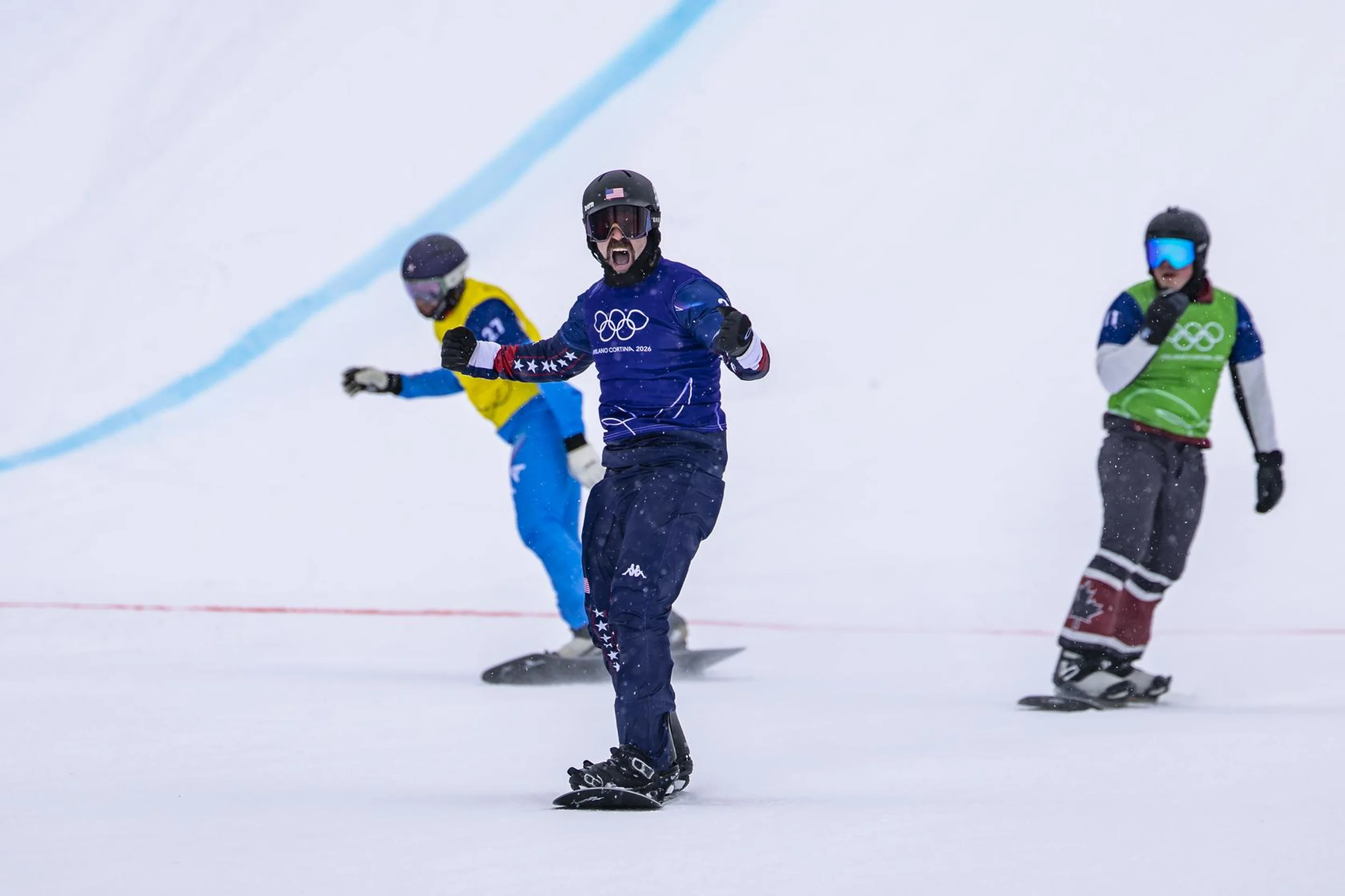 Three snowboarders in colorful outfits on a snowy slope during a race, each wearing a helmet and goggles.