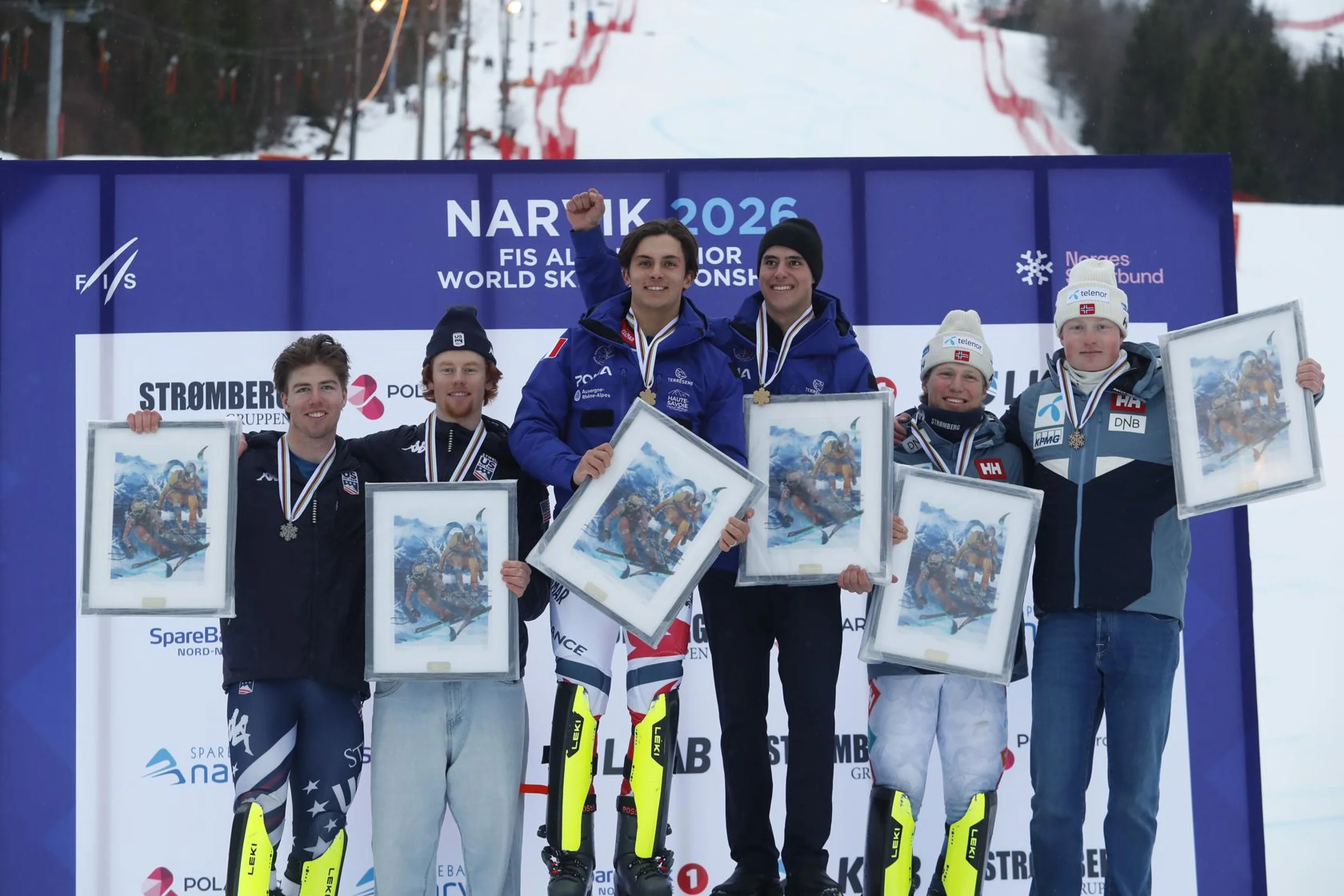 The Team Combined medalists holding framed artwork and medals, standing on a podium with a snowy slope and banners in the background.