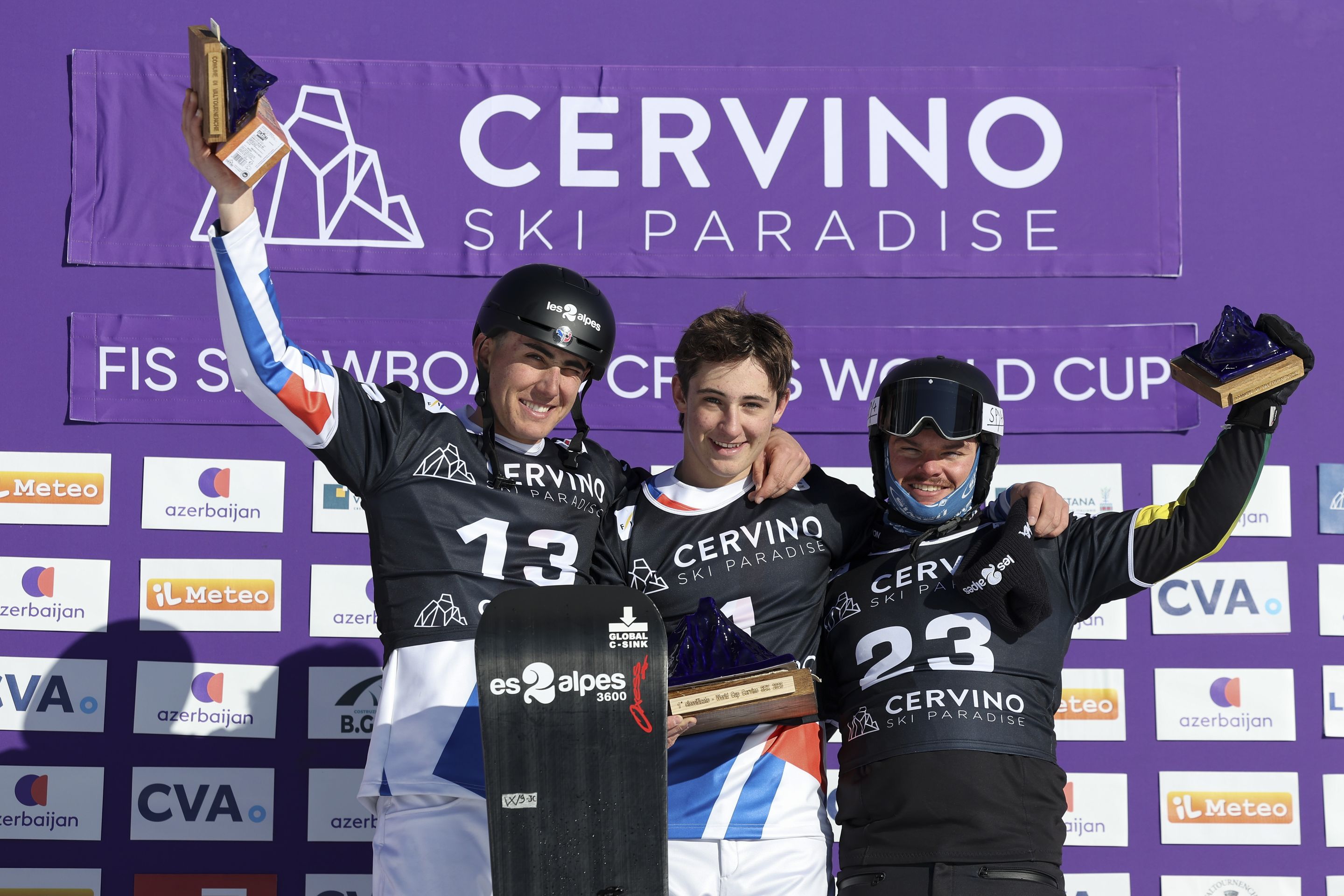 Aidan and Jonas Chollet (FRA) and Adam Lambert (AUS) celebrate on the podium in Cervinia, standing in front of a purple backdrop