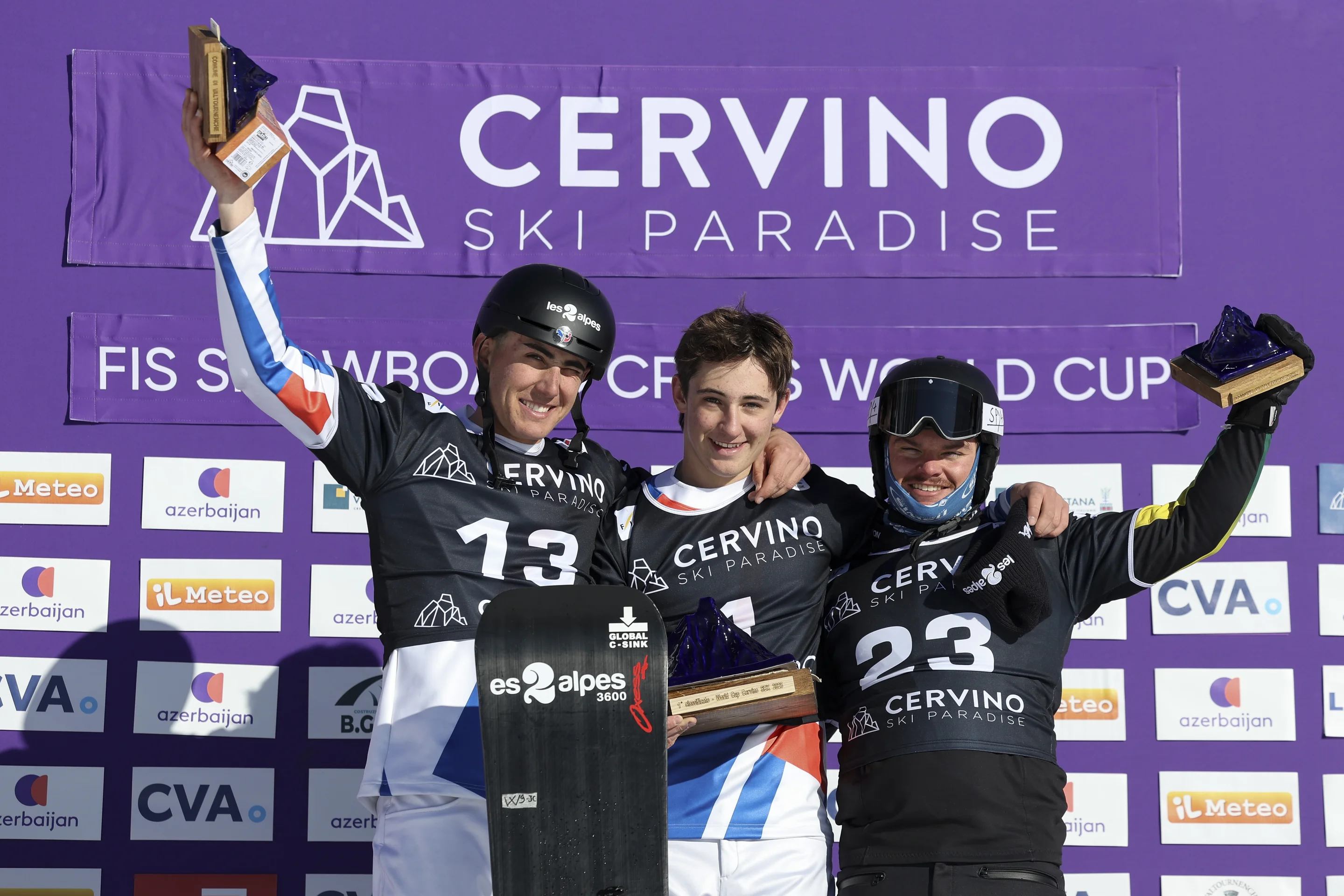 Aidan and Jonas Chollet (FRA) and Adam Lambert (AUS) celebrate on the podium in Cervinia, standing in front of a purple backdrop