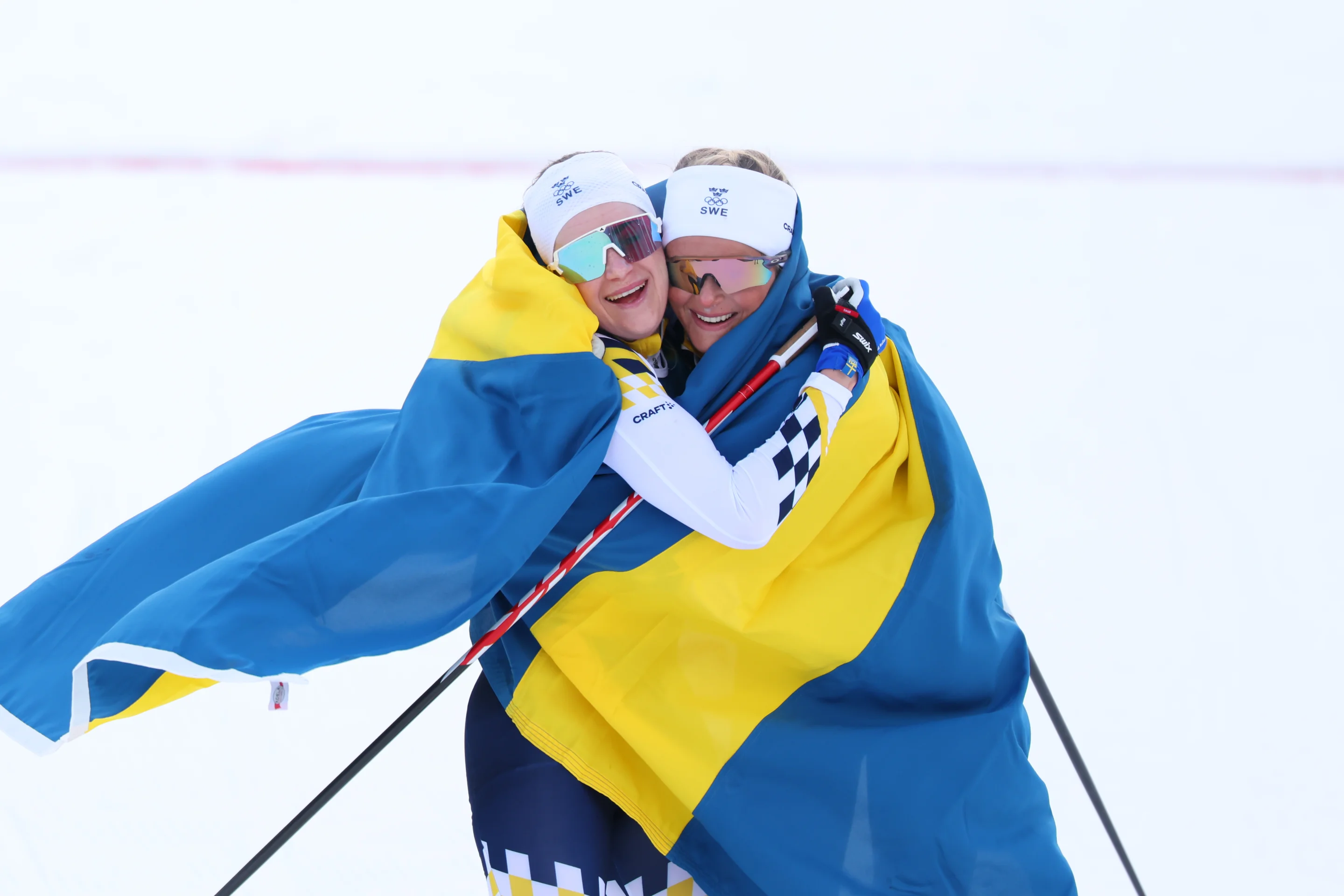 Ebba Andersson (right) and Frida Karlsson embrace while wrapped in the Swedish flag