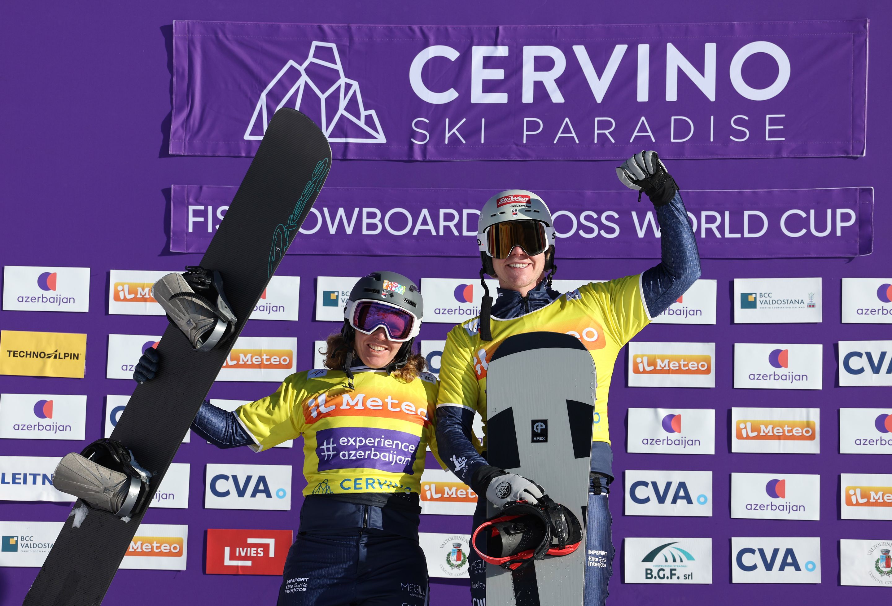 Wearing yellow bibs in front of a purple background, Charlotte Bankes and Huw Nightingale (GBR) celebrate Mixed Team victory in Cervinia
