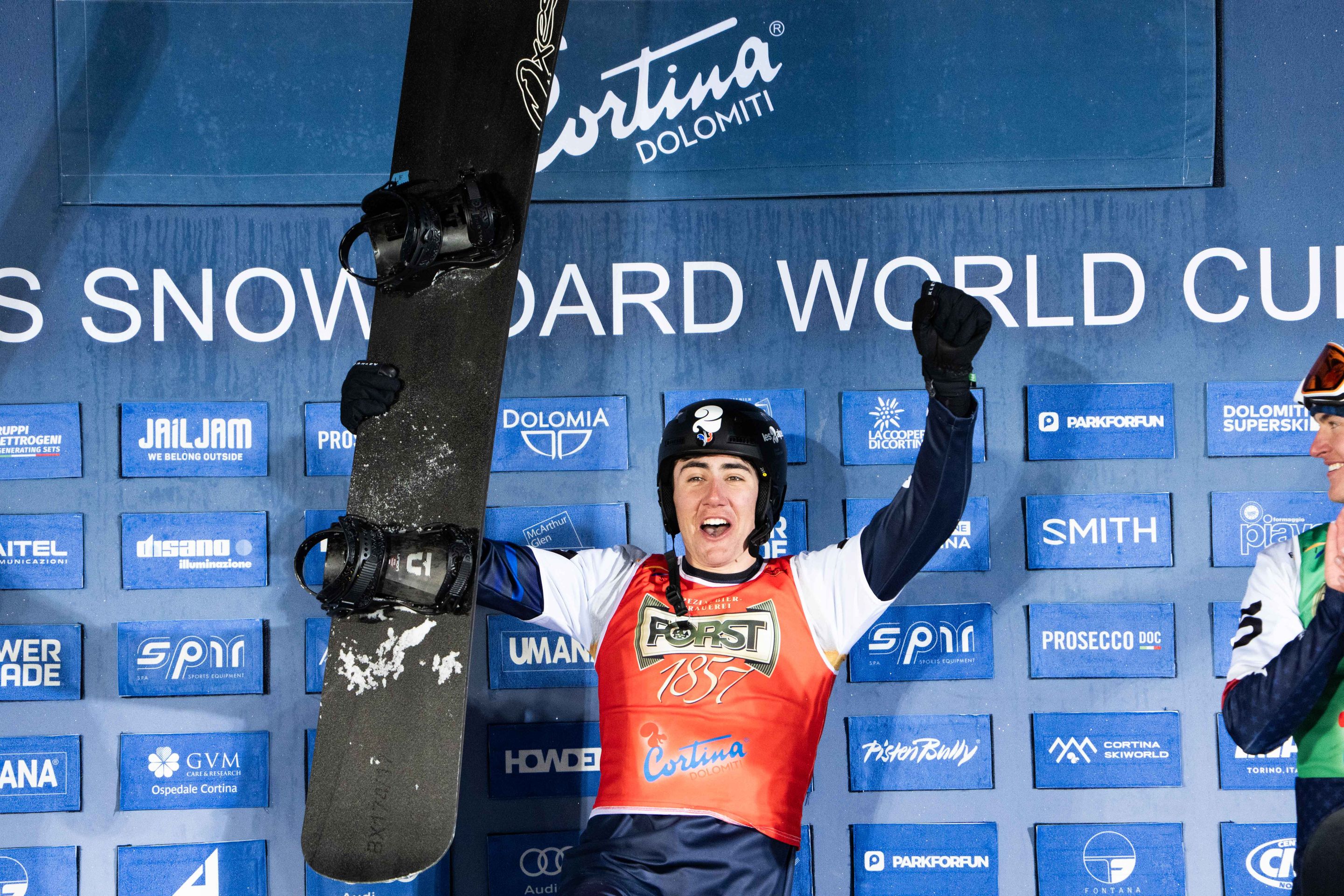 Aidan Chollet, wearing a red bib in front of a blue backdrop, celebrates victory in Cortina in February 2025
