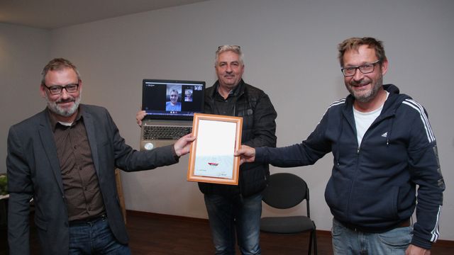 Alexander Ziron (rechts) nimmt von Manfred Deckert, Heiko Krause (im Video) und Andreas Kunoth (links) Glückwünsche zur Auszeichnung mit der DSV-Ehrennadel in Silber entgegen. Foto: Brand-Aktuell