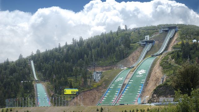 The entry sign greets visitors to Utah Olympic Park in Park City, Utah June 26, 2003. The K90 and k120 ski jump hills are visible in the background.