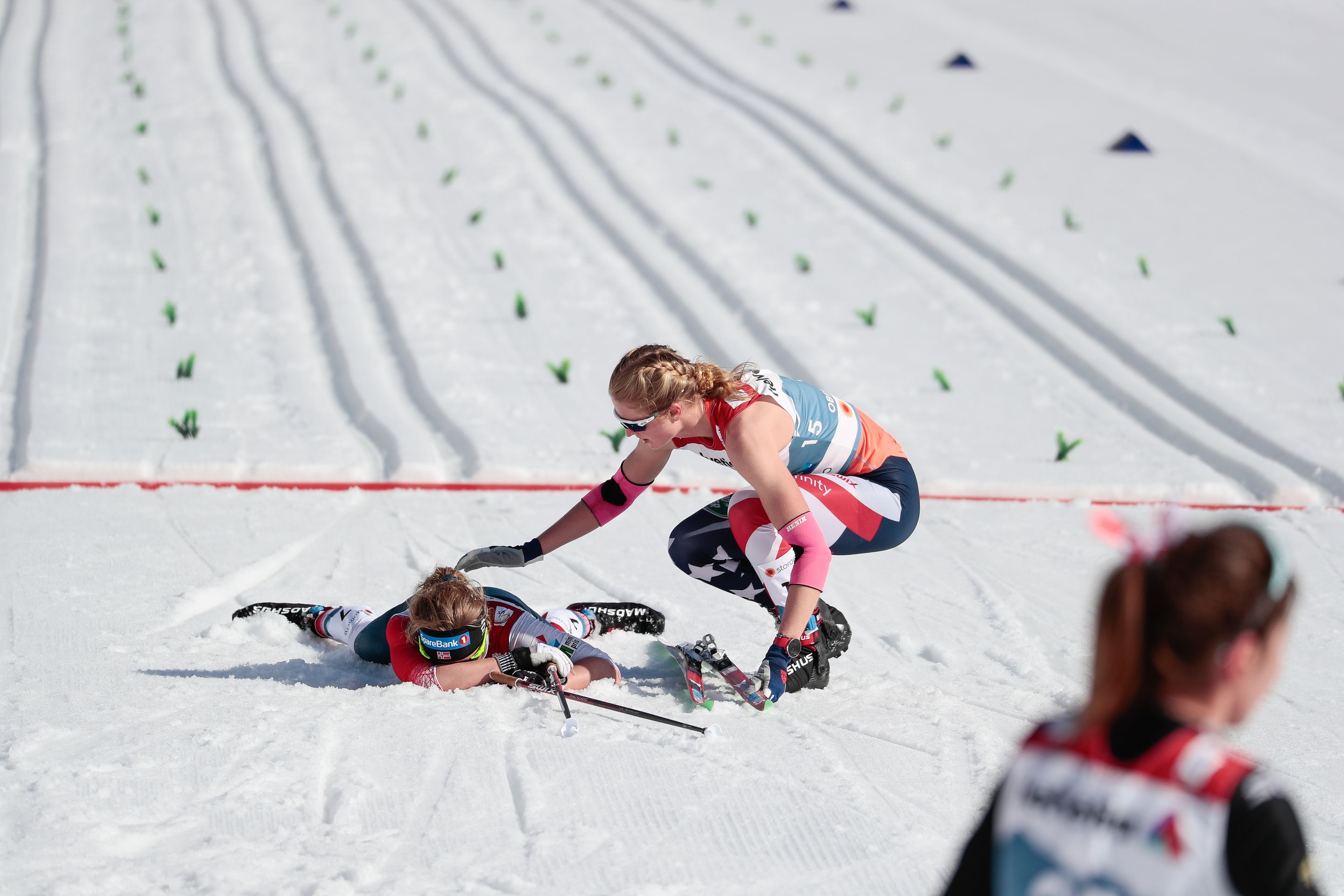 Hailey checking on Marie Helene Fossesholm after the finish line of Oberstdorf's 30km Mst | Image by NordicFocus